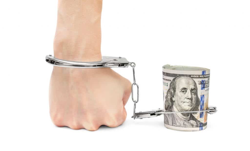 Hand chained to money by handcuffs. Isolated on white.