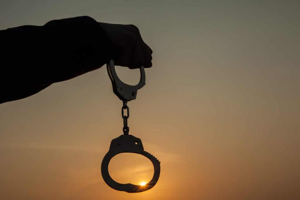 Business Man holding handcuffs after releasing over sunset background. Freedom and Burden-free concept